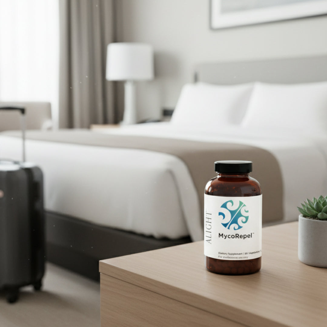 Mycorepel bottle on a nightstand in a hotel room with a bed and suitcase in the background.