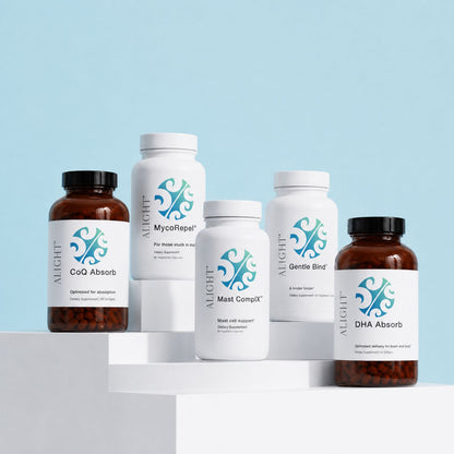 Five ALIGHT brand dietary supplement bottles arranged on white display blocks against a light blue background. The products include CoQ Absorb, MycoNapAq, Mast Complex, Gentle Bind, and DHA Absorb in amber and white bottles with white labels and teal logos.