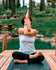 Women practicing yoga on a wooden platform with a natural landscape in the background