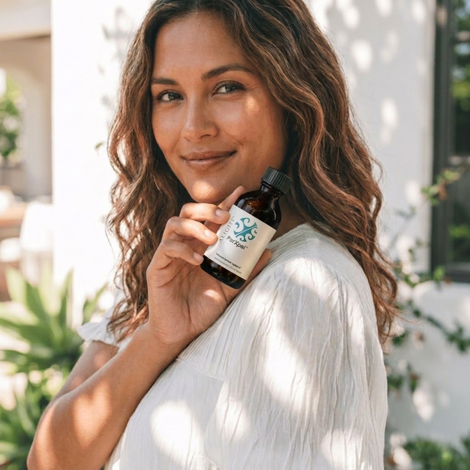 woman holding ParXpel bottle outdoors smiling at camera